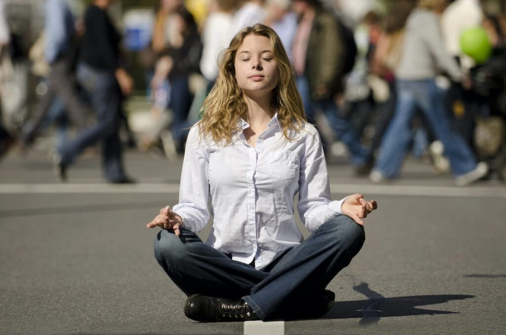 Mujer meditando en un espacio urbano concurrido libre de ansiedad porque toma myo inositol.