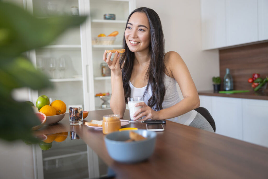 Mujer come desayuno y toma multivitaminicos holiherb para tener una salud equilibrada.