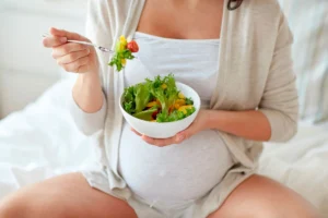 Una mujer embarazada come una ensalada como parte de su dieta para diabetes gestacional.