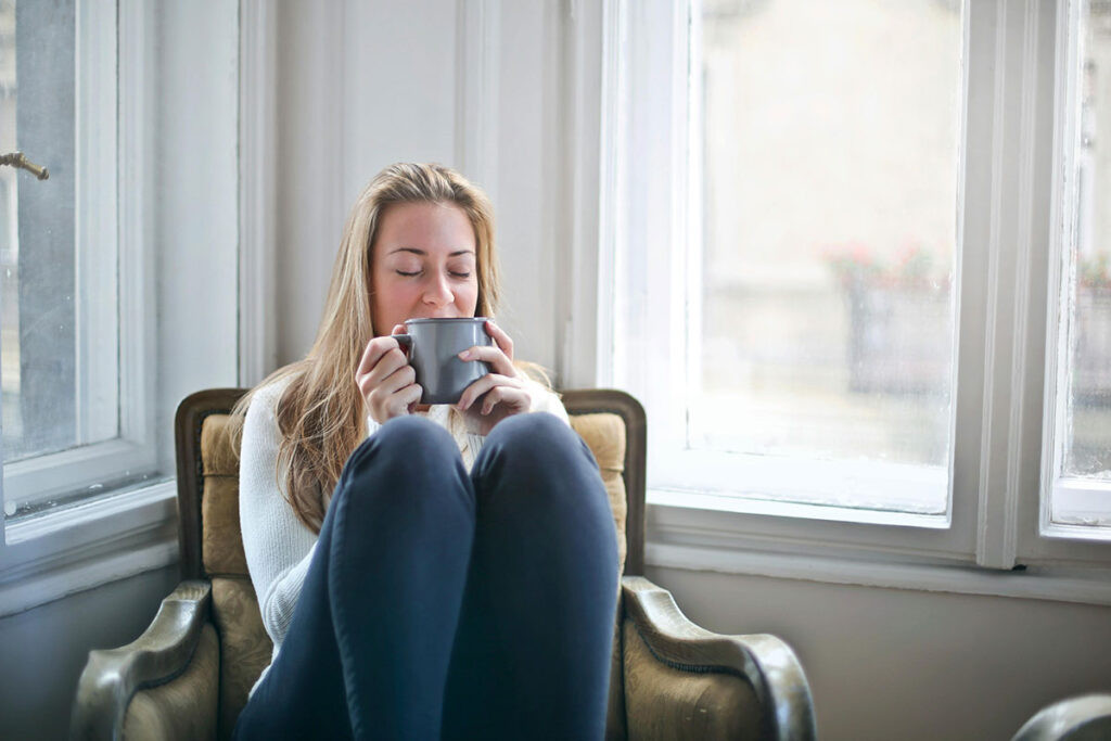 Mujer bebiendo una infusión para aliviar los dolores abdominales y la inflamación utilizando remedios naturales para la endometriosis