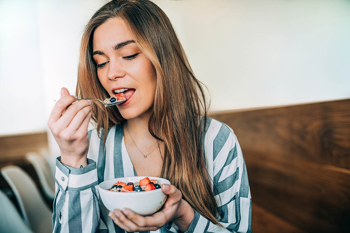 Mujer comiendo alimentos adecuados para cada fase de su ciclo menstrual logra equilibrio hormonal.