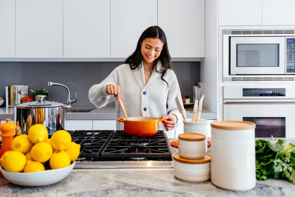 Mujer feliz cocinando alimentos saludables como parte de su dieta para endometriosis.