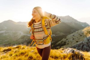Una mujer sonriente camina en la montaña muy saludable porque toma suplementos de EPA y DHA.