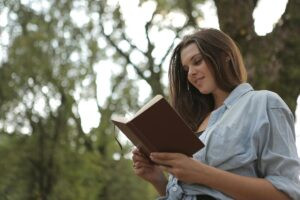 Mujer leyendo un libro al aire libre; con bienestar visual y protección gracias a la luteína y zeaxantina.