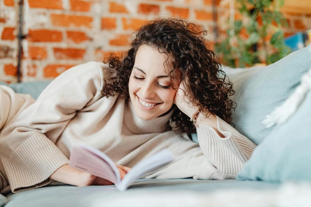 Mujer leyendo en el sofá con visión saludable gracias a consumir suplementos con luteína y zeaxantina.