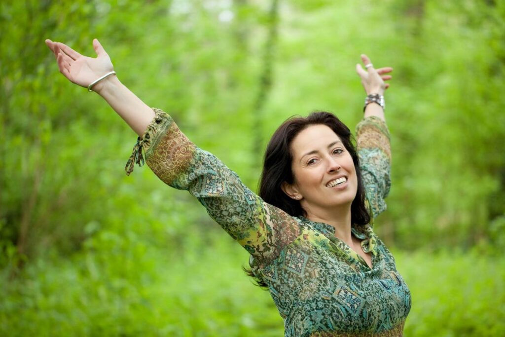 Mujer sonriente al aire libre representando el bienestar y equilibrio hormonal tras el uso de ácido alfa lipoico.